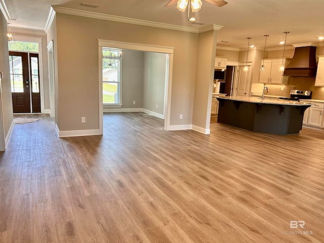 kitchen featuring stainless steel electric range oven, white cabinetry, hanging light fixtures, light hardwood / wood-style flooring, and premium range hood