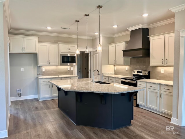 kitchen featuring sink, premium range hood, an island with sink, white cabinets, and appliances with stainless steel finishes