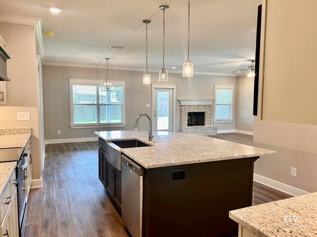 kitchen with range with electric stovetop, a kitchen island with sink, stainless steel dishwasher, and light stone counters