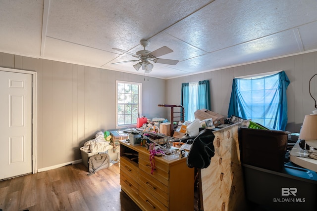 bedroom featuring hardwood / wood-style floors, ceiling fan, and wood walls