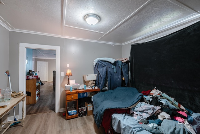 bedroom with a textured ceiling, hardwood / wood-style flooring, and ornamental molding