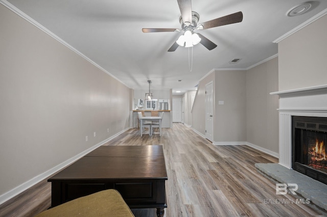 unfurnished living room featuring light hardwood / wood-style floors, ceiling fan, and crown molding