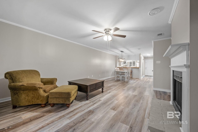 living room with light hardwood / wood-style flooring, ceiling fan, and ornamental molding