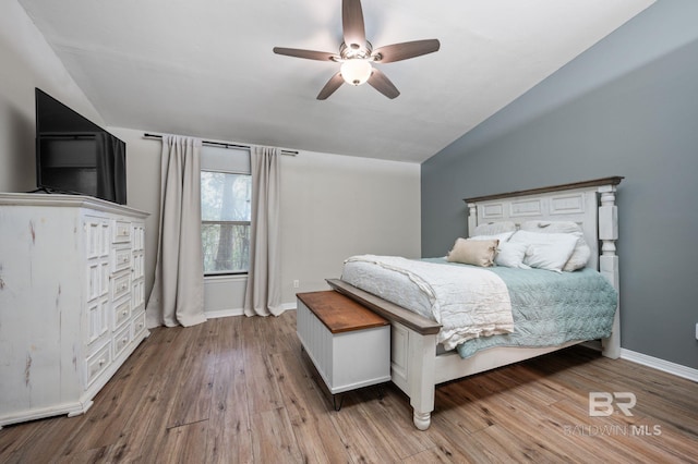 bedroom featuring ceiling fan, light hardwood / wood-style flooring, and lofted ceiling