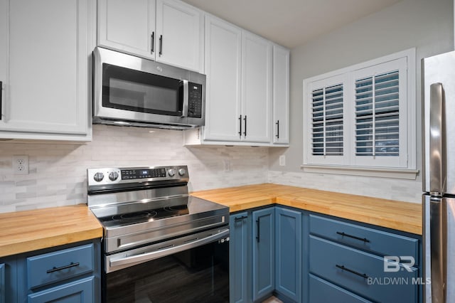 kitchen with blue cabinetry, stainless steel appliances, white cabinets, and butcher block counters