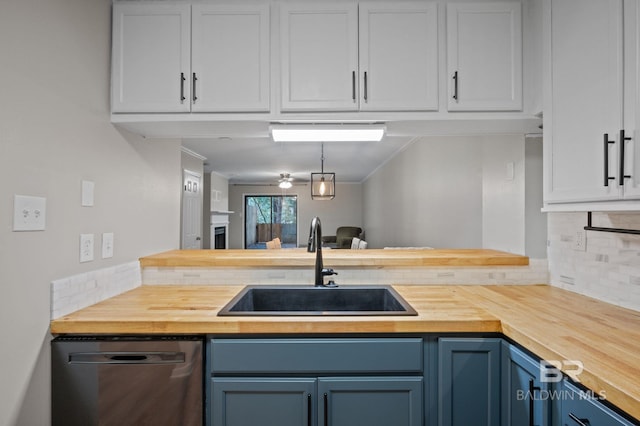 kitchen with sink, hanging light fixtures, wooden counters, stainless steel dishwasher, and blue cabinets