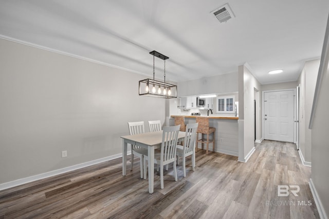 dining room featuring hardwood / wood-style floors, ornamental molding, and sink