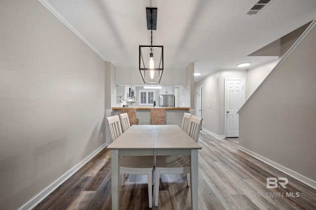 dining room featuring light hardwood / wood-style flooring and crown molding