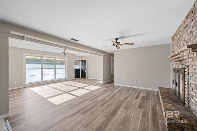 unfurnished living room with ceiling fan, a fireplace, and light hardwood / wood-style flooring