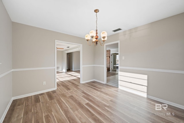 unfurnished dining area featuring wood-type flooring and a notable chandelier