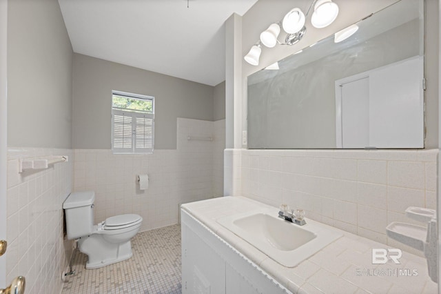 bathroom featuring tile patterned floors, vanity, toilet, and tile walls