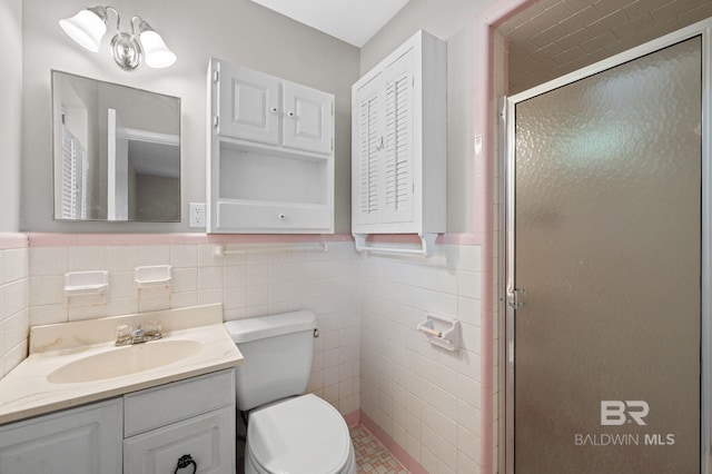 bathroom featuring vanity, toilet, tile walls, and a shower with shower door