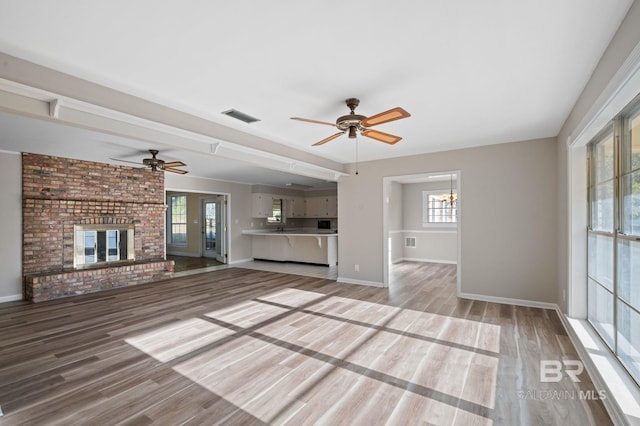 unfurnished living room featuring hardwood / wood-style floors, a brick fireplace, and ceiling fan