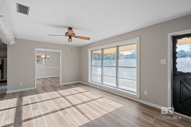 unfurnished living room featuring hardwood / wood-style floors and ceiling fan with notable chandelier