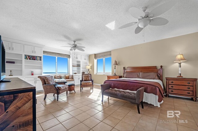 bedroom featuring ceiling fan, a textured ceiling, and multiple windows