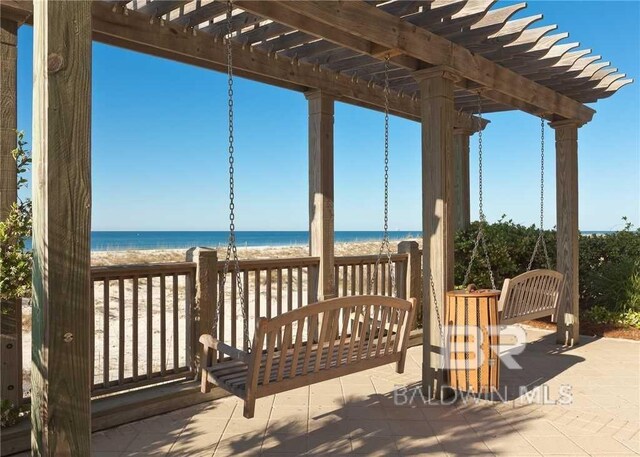 view of patio featuring a water view, a pergola, and a beach view