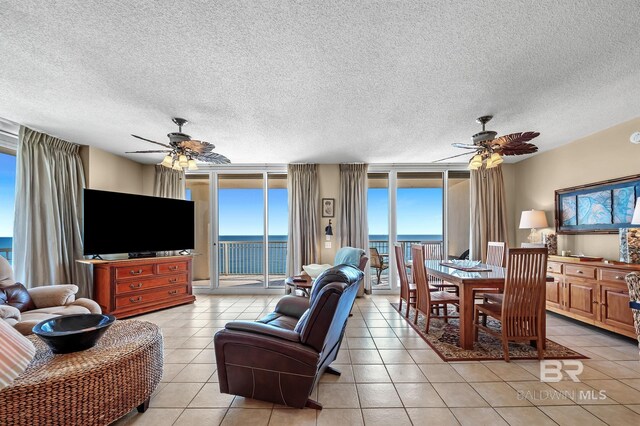 living room with ceiling fan, a textured ceiling, floor to ceiling windows, and light tile patterned flooring