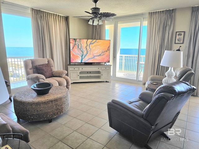 living room with light tile patterned floors, ceiling fan, and a textured ceiling