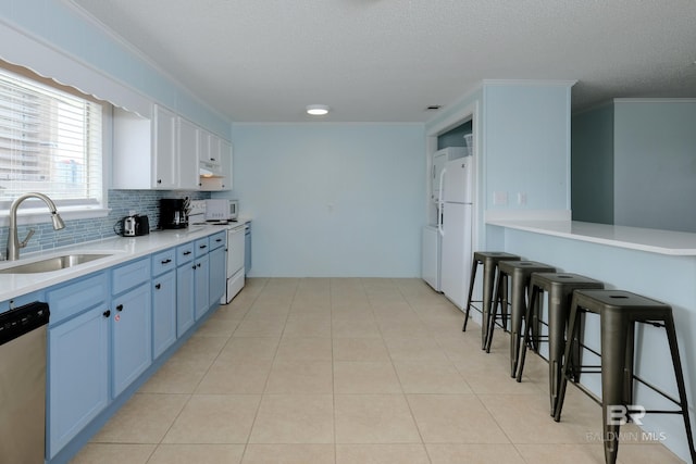 kitchen with white cabinets, light tile patterned floors, white appliances, and sink