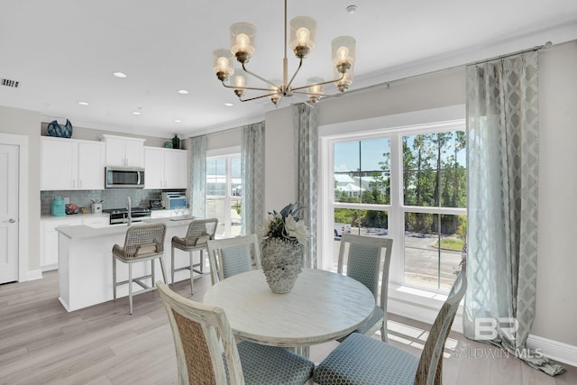 dining area with baseboards, recessed lighting, ornamental molding, light wood-type flooring, and a chandelier