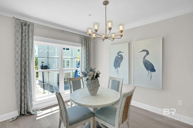 dining room with baseboards, a notable chandelier, wood finished floors, and crown molding