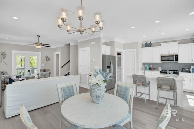 dining area featuring stairway, light wood-type flooring, ornamental molding, recessed lighting, and ceiling fan with notable chandelier