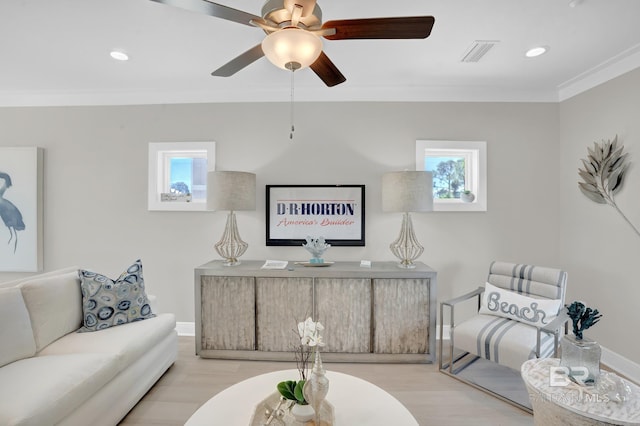 living area featuring baseboards, wood finished floors, visible vents, and ornamental molding