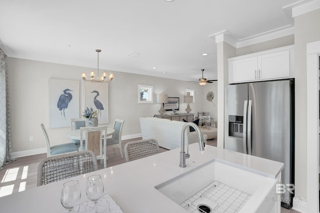 kitchen with baseboards, a sink, light countertops, white cabinets, and stainless steel fridge