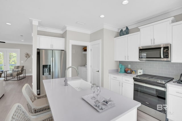 kitchen with a sink, decorative backsplash, crown molding, and stainless steel appliances