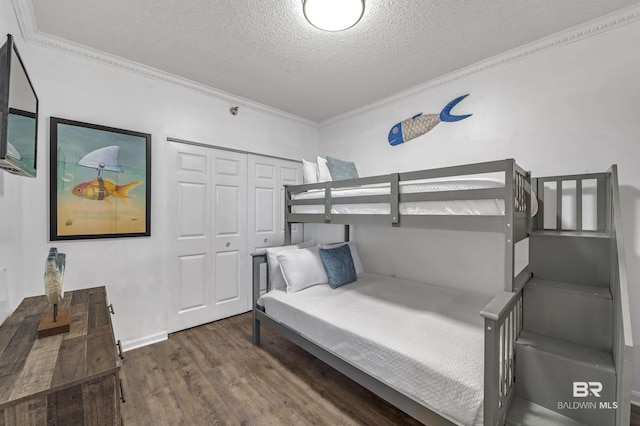 bedroom with a textured ceiling, a closet, ornamental molding, and wood finished floors