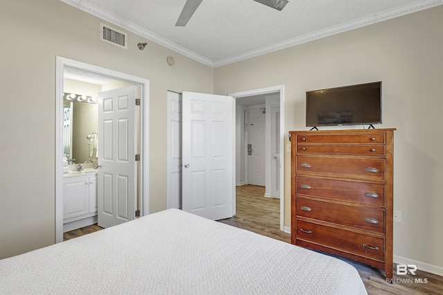 bedroom with visible vents, ornamental molding, wood finished floors, and ensuite bathroom