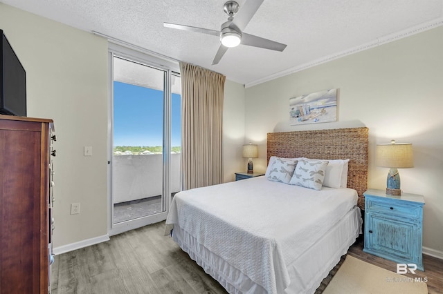 bedroom featuring access to outside, a textured ceiling, baseboards, and wood finished floors