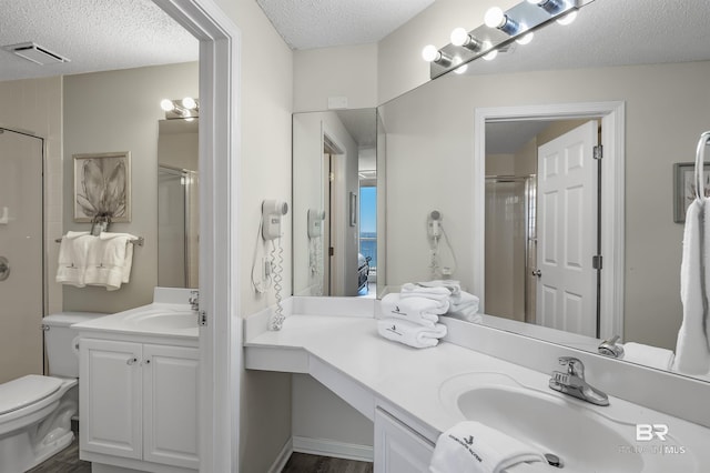 full bath featuring visible vents, toilet, a textured ceiling, a shower stall, and vanity