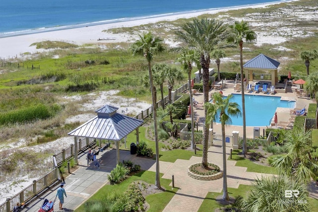 pool with a beach view, a water view, fence, a gazebo, and a patio area