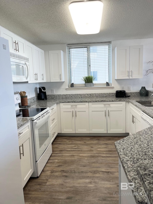 kitchen featuring a textured ceiling, white appliances, dark wood-style flooring, and white cabinetry