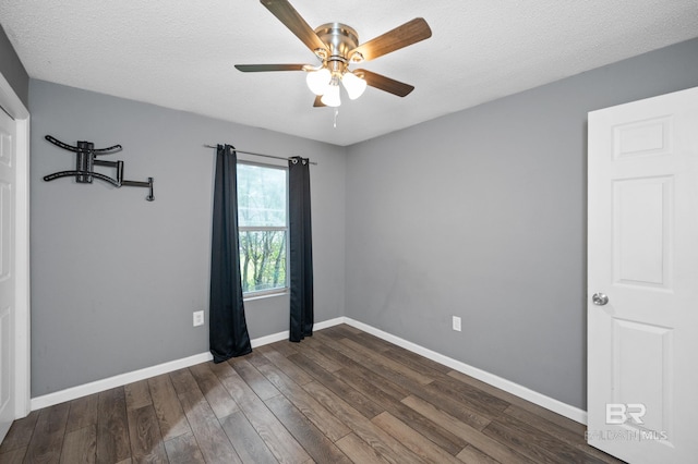 spare room featuring a textured ceiling, dark wood-type flooring, and ceiling fan