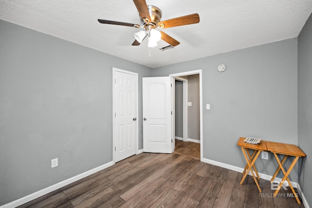 unfurnished room featuring ceiling fan, a textured ceiling, and dark hardwood / wood-style flooring