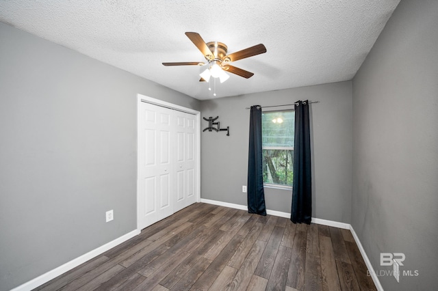 unfurnished bedroom featuring dark hardwood / wood-style flooring, a closet, a textured ceiling, and ceiling fan