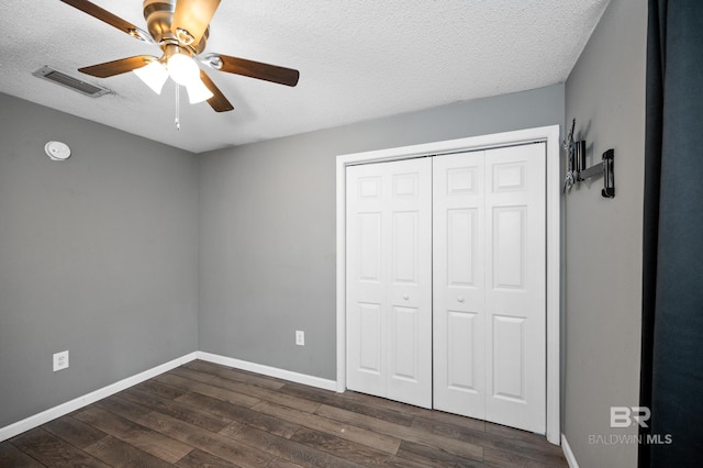 unfurnished bedroom with dark hardwood / wood-style flooring, a closet, a textured ceiling, and ceiling fan