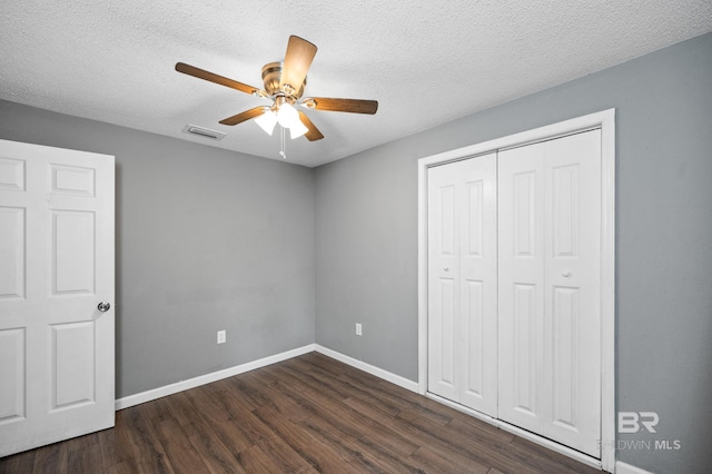 unfurnished bedroom featuring dark wood-type flooring, a closet, a textured ceiling, and ceiling fan