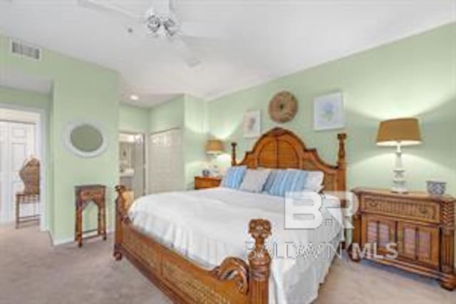 bedroom featuring ceiling fan, a closet, light carpet, and connected bathroom