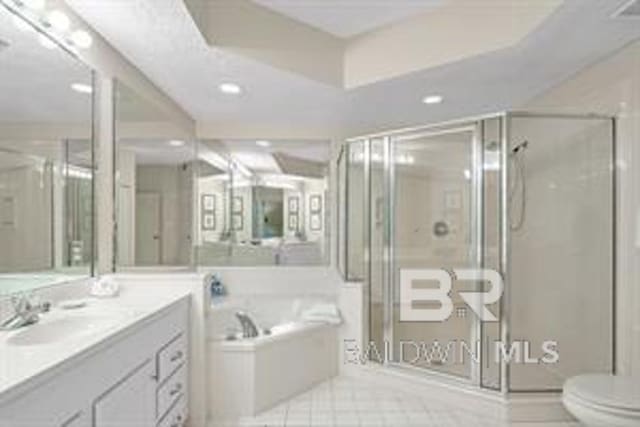 full bathroom with separate shower and tub, tile floors, toilet, and vanity with extensive cabinet space