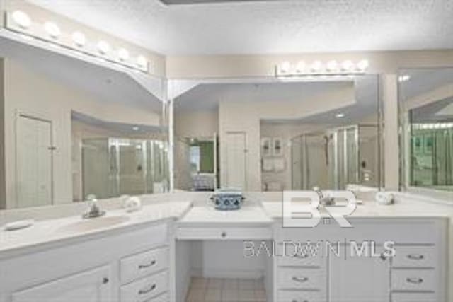 bathroom featuring a textured ceiling, tile floors, a shower with shower door, and oversized vanity