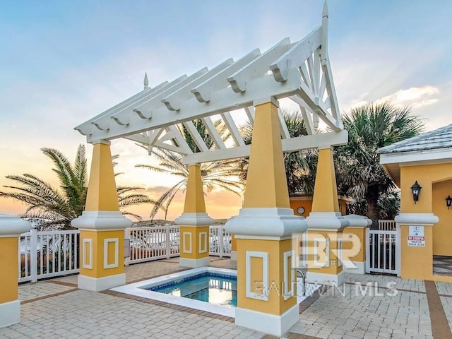 back house at dusk with a pergola, a patio area, and a pool