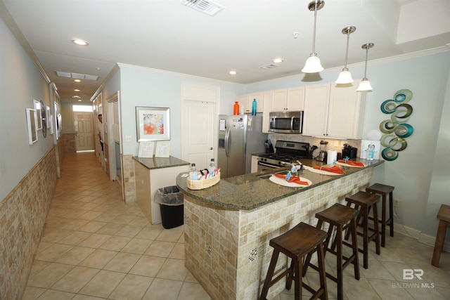 kitchen with pendant lighting, a breakfast bar, appliances with stainless steel finishes, light tile patterned flooring, and kitchen peninsula