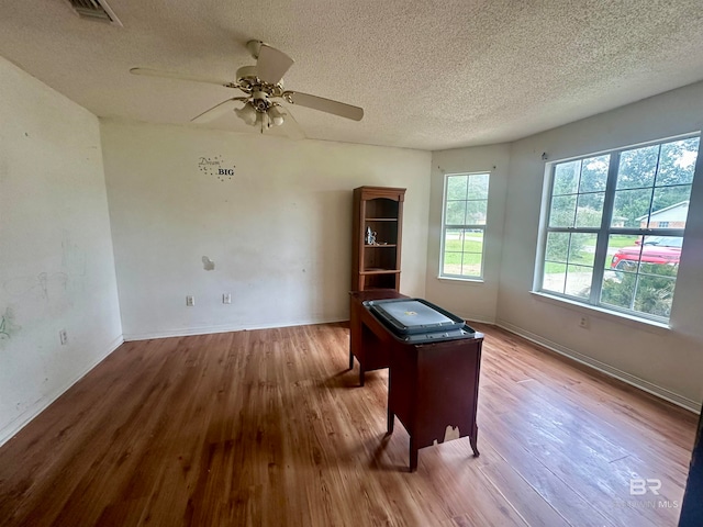 interior space with ceiling fan, wood-type flooring, and a textured ceiling