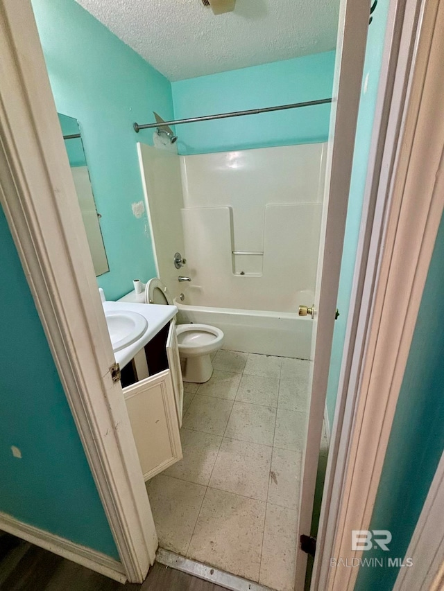 full bathroom with shower / bathing tub combination, vanity, a textured ceiling, and toilet