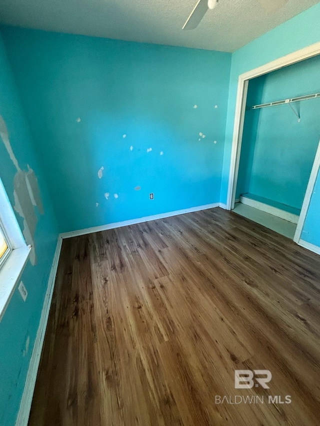 unfurnished bedroom with wood-type flooring, a textured ceiling, a closet, and ceiling fan