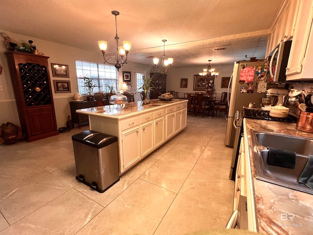 kitchen with a textured ceiling, a center island, decorative light fixtures, and a notable chandelier