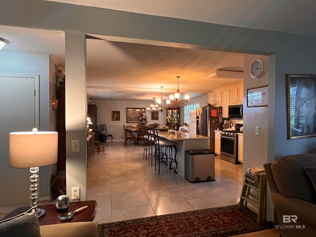 kitchen with pendant lighting, a center island, white cabinets, a kitchen breakfast bar, and appliances with stainless steel finishes